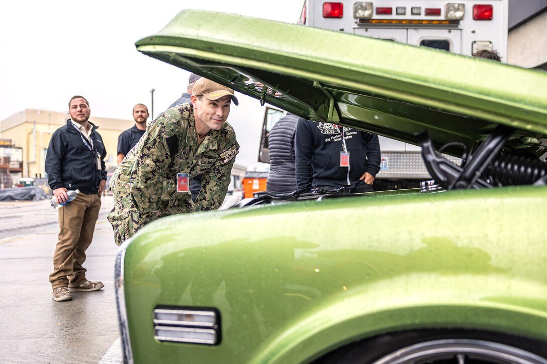 Capt. JD Crinklaw, commander, Puget Sound Naval Shipyard & Intermediate Maintenance Facility, admires the 454 BB engine in a 1969 Chevy C10 truck, June 23, 2024, at PSNS & IMF "Pathway To Safety" training event in Bremerton, Washington. (U.S. Navy photo by Jeb Fach)