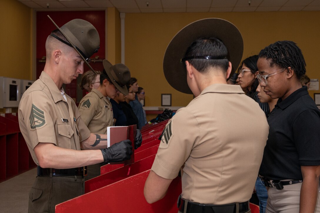 U.S. Marine Corps Sgt. Veronica Luevanos, front, Staff Sgt Christopher Javner, middle, Sgt Natali Moreno, back, drill instructors with Receiving Company, Support Battalion, inspect for contraband as part of a receiving event for the recruits with Fox Company, 2nd Recruit Training Battalion, at Marine Corps Recruit Depot San Diego, California, June 24, 2024. During the receiving process recruits are checked for contraband, given haircuts, make a scripted phone call home, and are issued their gear required for training. (U.S. Marine Corps photo by Lance Cpl. Janell B. Alvarez)