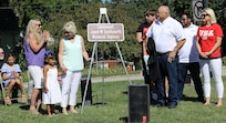 Kim and Bob Southworth unveil the highway sign honoring their son with family during a dedication ceremony on July 6 as a section of State Highway 133 through Oakland, Illinois, was named the 1st Lt. Jared W. Southworth Highway.