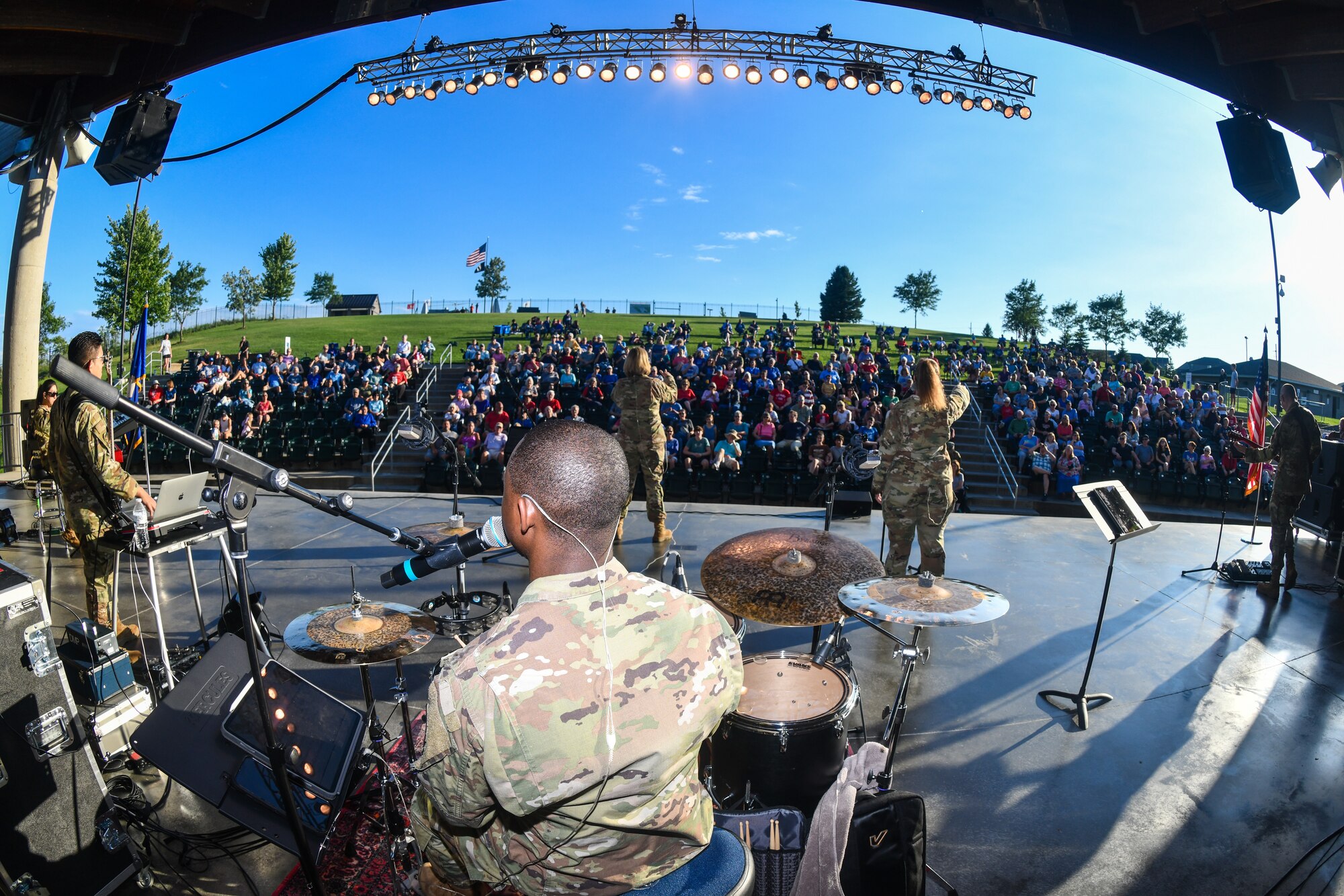 a view from behind a band in military uniform performing for a crowd of people