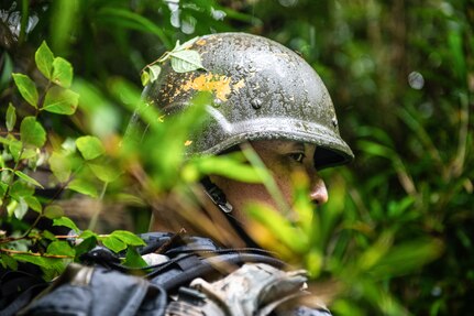 Japanese military member scans his surroundings as his team navigates through an overgrown terrain.