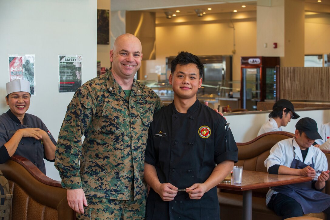 U.S. Marine Corps Lt. Col David Hunley, left, the director of food services for Marine Corps Installations Command, poses for a photo with Lance Cpl. Ya Koo, a food service specialist with Headquarters and Headquarters Squadron, Marine Corps Air Station Iwakuni, after giving him a challenge coin for outstanding work while taking part in the Maj. Gen. William Pendleton Thompson (W.P.T.) Hill memorial awards program at MCAS Iwakuni, Japan, Jan. 29, 2024. The W.P.T. Hill awards program aims to acknowledge outstanding performance within Marine Corps food service operations, including determining and recognizing the best mess halls of the year.