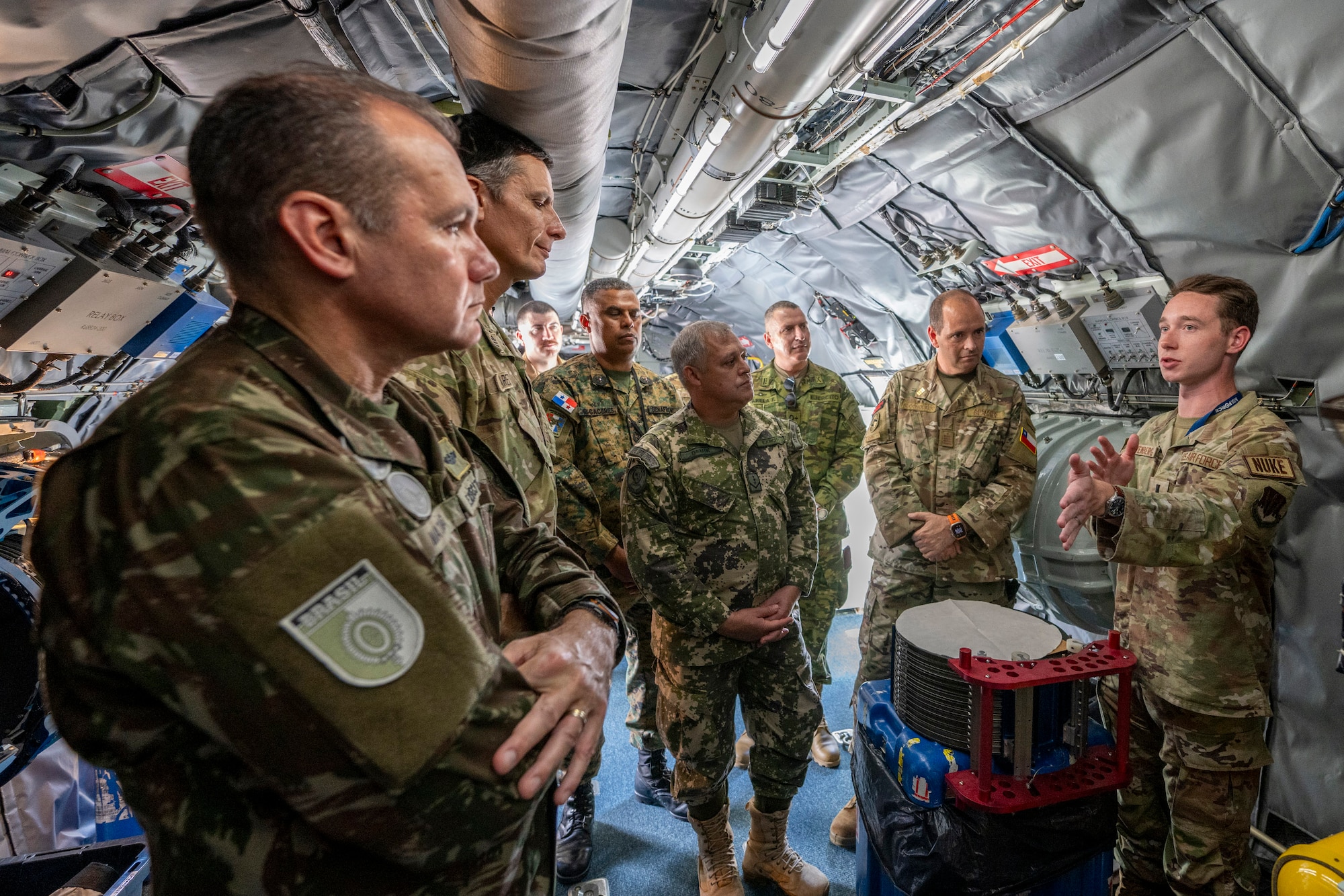 1st Lt. Jacob Weinberg, a nuclear response officer for the 21st Surveillance Squadron, briefs several foreign liaison officers assigned to U.S. Southern Command during their visit to Homestead Air Reserve Base, Fla.  The FLOs toured the Air Force Technical Applications Center’s nuclear debris collection aircraft, the WC-135 Constant Phoenix, June 25, 2024, to learn more about the jet’s capabilities.  (U.S. Air Force photo by Matthew S. Jurgens)