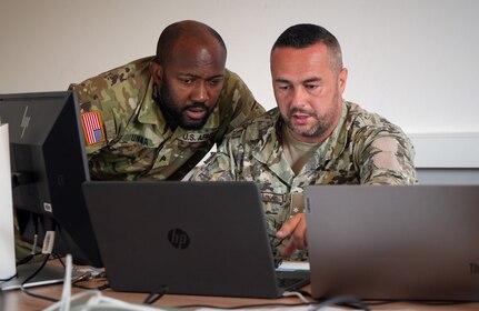 Maryland Army National Guard Sgt. Emmanuel Unaka, cyber threat intelligence analyst with Cyber Protection Team 169, listens to Armed Forces of Bosnia and Herzegovina Lt. Armin Kolašinac, a Security Operations Center member, during the Adriatic Regional Security Cyber Cooperation exercise at the Slovenian Armed Forces Baron Andrej Čehovin barracks in Postojna, Slovenia, July 5, 2024. The two-week cybersecurity training event included representatives from six Adriatic nations working alongside their U.S. National Guard counterparts.