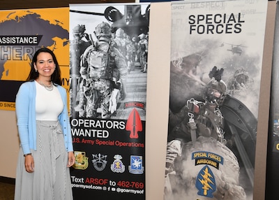 A woman stands next to pull up banner encouraging people to apply to the Army Special Forces.