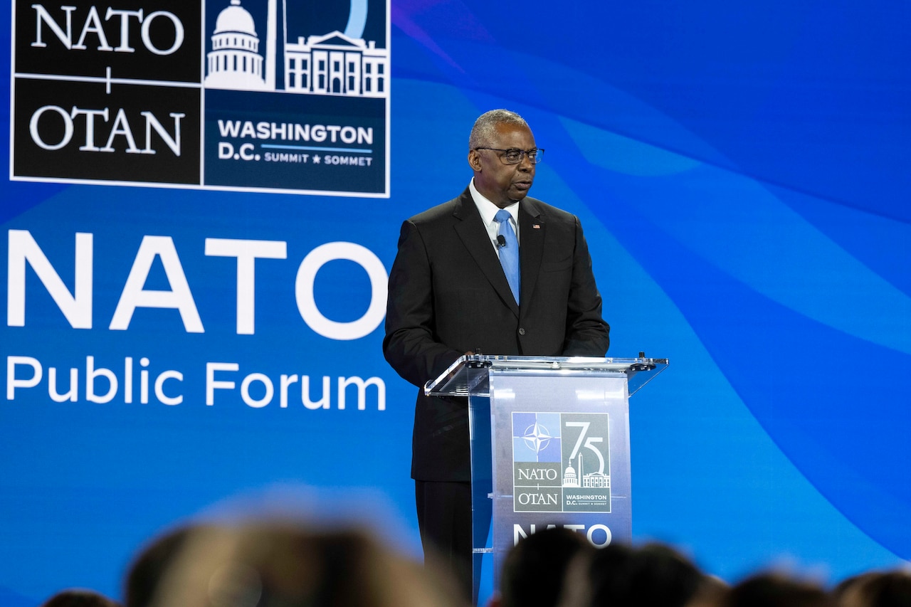 A civilian stands behind a podium and speaks.