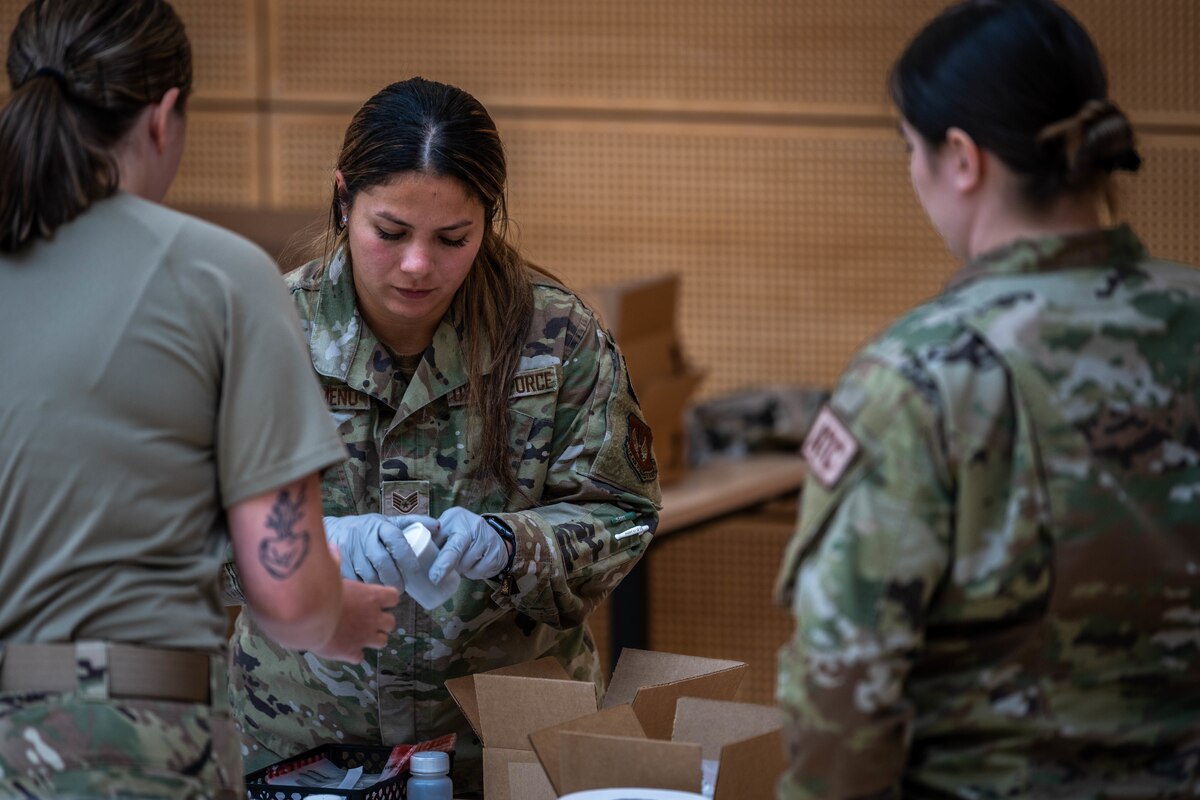 A urinalysis monitor reviews urinalysis samples while Airmen wait in front of her inside a gym.