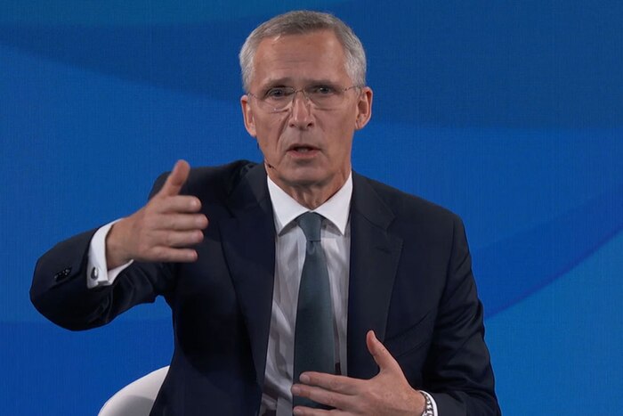 A person dressed in a business suit motions with their hands.