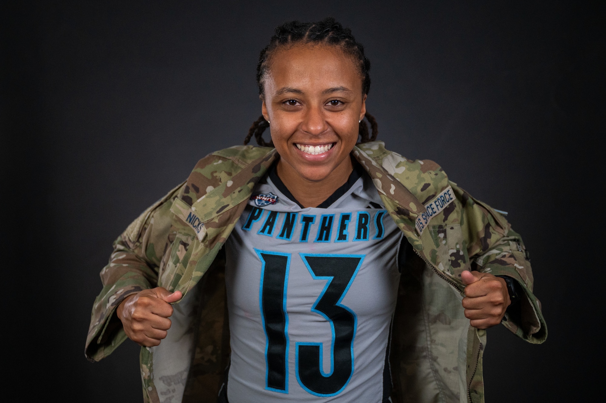 A woman holds her U.S. Space Force uniform top over a football jersey.