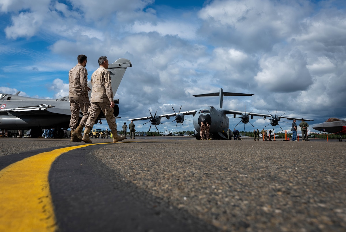 2 members from the Spanish Air Force walk on the flightline in front of a German static display aircraft.
