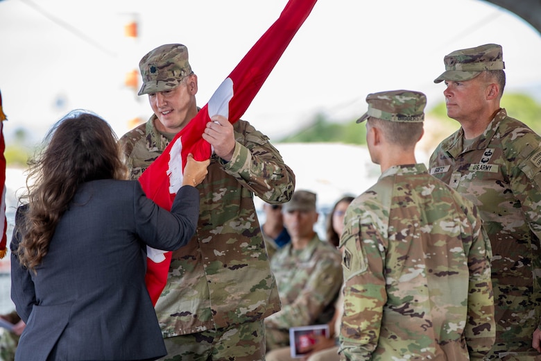 Lt. Col. Christopher “Ryan” Pevey, outgoing District Commander for the U.S. Army Corps of Engineers Honolulu District, receives the unit colors from the Deputy District Engineer for Programs & Project Management Jennifer Moore, before symbolically relinquishing command by passing the unit colors to Brig. Gen. Joseph C. “Clete” Goetz II, Commanding General for the U.S. Army Corps of Engineers Pacific Ocean Division in a July 10 ceremony aboard the Battleship Missouri Memorial.