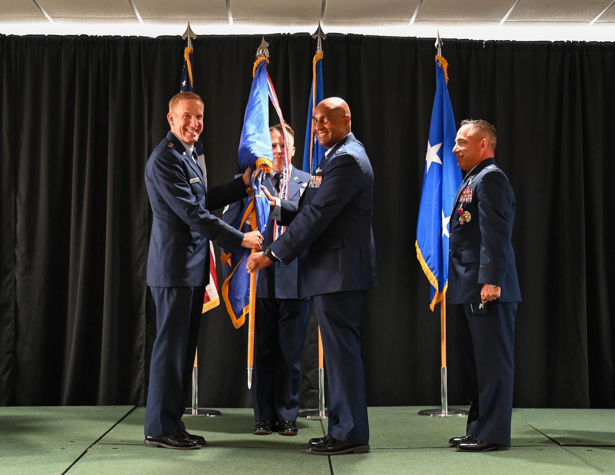 U.S. Air Force Maj. Gen. Case Cunningham, U.S. Air Force Warfare Center commander, left, passes the guidon to U.S. Air Force Col. Larry Fenner Jr., 350th Spectrum Warfare Wing incoming commander, center, during the wing change of command ceremony at Eglin Air Force Base, Florida, July 9, 2024. Fenner took command in the wing’s third change of command ceremony since its activation in 2021, and will lead 15 units across four installations. (U.S. Air Force photo by Senior Airman Anna Smith)