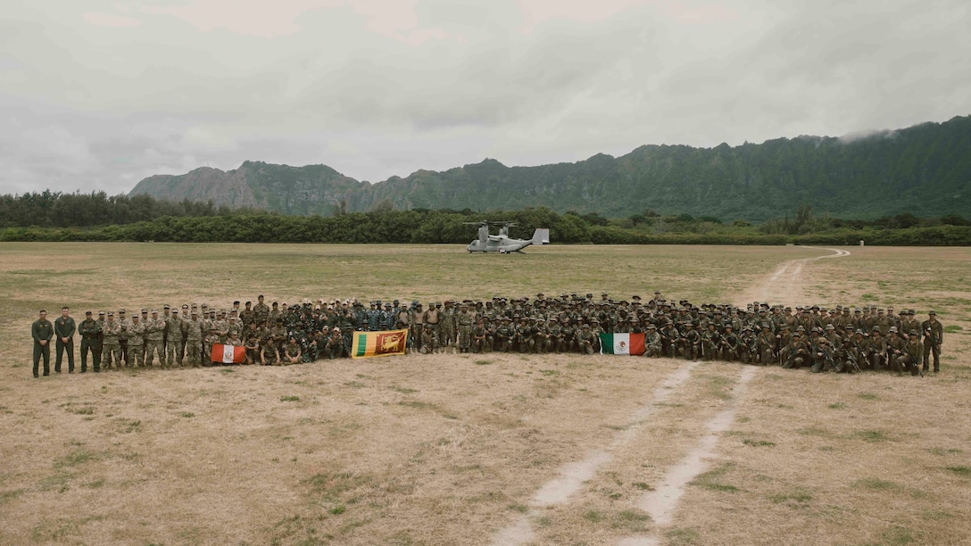 U.S. Marine Corps Lt. Col. Geoffrey Blumenfled, the commanding officer of Marine Medium Tiltrotor Squadron 363, Marine Aircraft Group 24, 1st Marine Aircraft Wing, left, poses for a group photo after Marines with Bravo Company, Battalion Landing Team 1/5, 15th Marine Expeditionary demonstrated a fast-rope insertion to partner forces at Marine Corps Training Area Bellows, Waimanalo, Hawaii, as part of Exercise Rim of the Pacific 2024, July 2. Lt. Col. Blumenfled piloted the MV-22B Osprey while 15th MEU Marines demonstrated to partner forces the ability to conduct fast-rope insertions in austere locations. Twenty-nine nations, 40 surface ships, three submarines, 14 national land forces, more than 150 aircraft, and 25,000 personnel are participating in and around the Hawaiian Islands, June 27 to Aug. 1. The world's largest international maritime exercise; RIMPAC provides a unique training opportunity while fostering and sustaining cooperative relationships among participants critical to ensuring the safety of sea lanes and security on the world's oceans. RIMPAC 2024 is the 29th exercise in the series that began in 1971. (U.S. Marine Corps photo by Cpl. Joseph Helms)