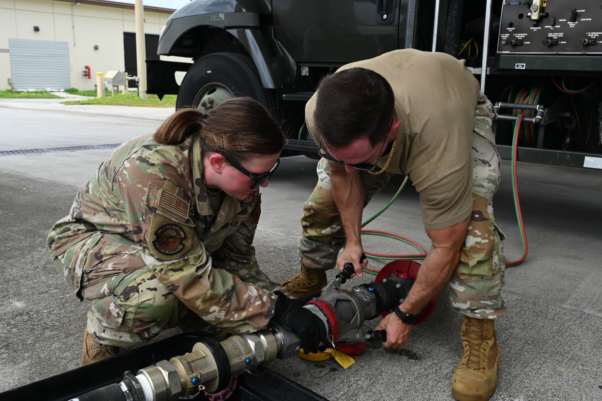 Two Airmen work together to attach a Versatile Integrating Partner-Nation Equipment Refueling (VIPER) hose to the single point receptacle.