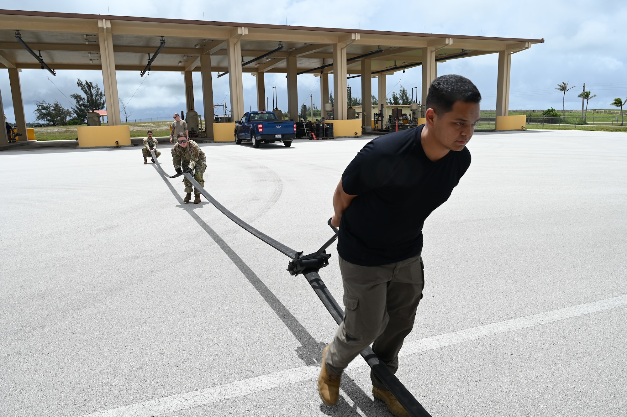 Two Airmen and a civilian work together to squeeze out any remaining fuel in a large house while also using a squeegee tool.