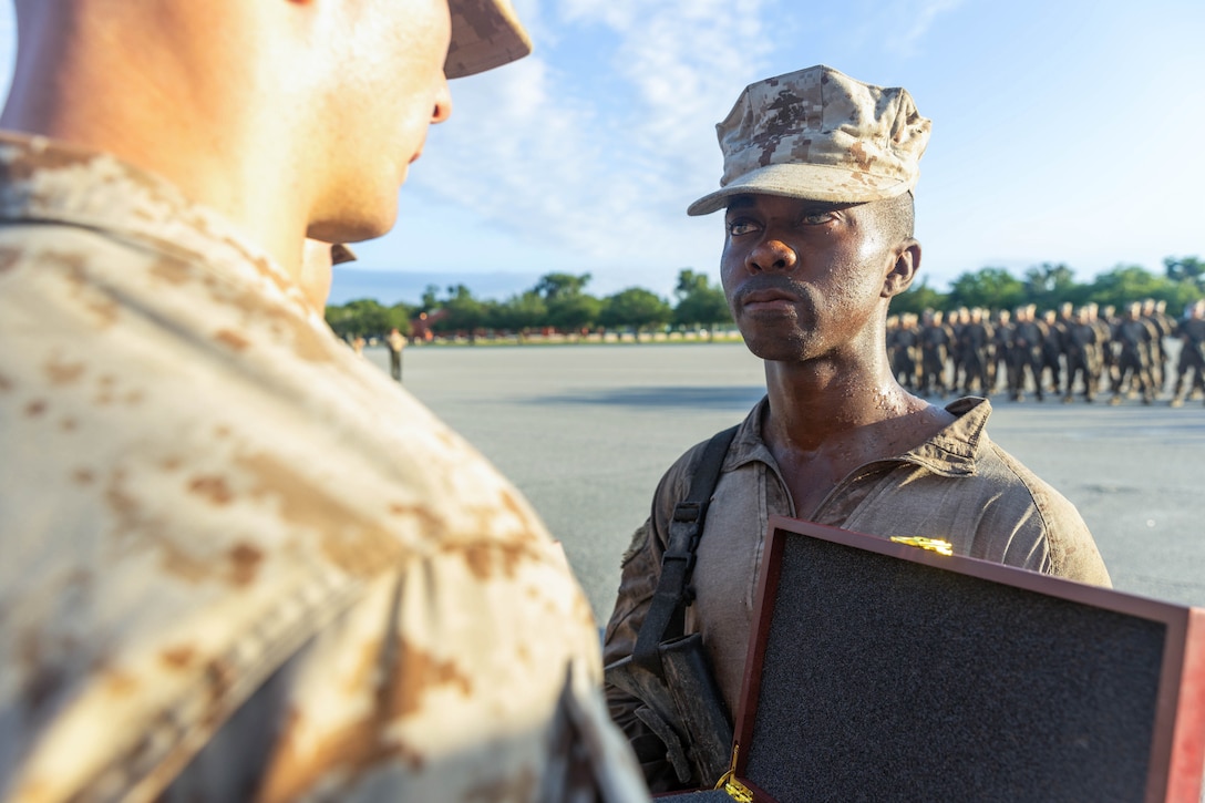 U.S. Marine Corps Pvt. Oluwagbemiga Omotoye, a Marine with Echo Company, 2nd Recruit Training Battalion, is given his Eagle, Globe, and Anchor from his drill instructor, Sgt. Devon Evoldi, on Marine Corps Recruit Depot Parris Island, S.C., June 29, 2024. The giving of the EGA signifies the transformation from recruit to United States Marine. (U.S. Marine Corps photo by Lance Cpl. William Horsley)