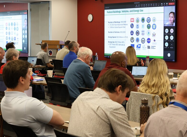 People sitiing at a table viewing a MS Teams screen.