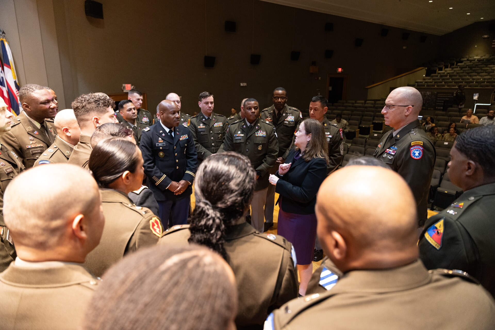 group of men and women wearing U.S. Army uniforms standing in a group talking.