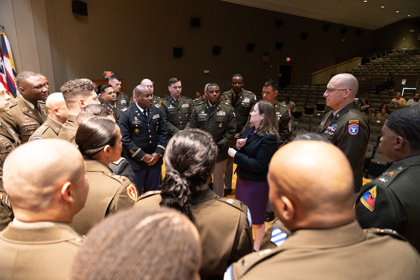 group of men and women wearing U.S. Army uniforms standing in a group talking.
