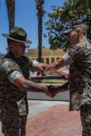 U.S. Marine Corps Maj. Sean Kierman, the executive officer of 3rd Recruit Training Battalion, Recruit Training Regiment, hands Staff Sgt. Jose Salcedo, a chief drill instructor with Kilo Company, 3rd Recruit Training Battalion, his meritorious promotion warrant at Marine Corps Recruit Depot San Diego, California, July 2, 2024. Salcedo was meritoriously promoted to the rank of staff sergeant for his hard work, dedication to duty, and excelling beyond his peers.  Meritorious promotions are based on outstanding performance and the Marine's ability to take on more responsibility and authority. Nominees must also demonstrate leadership skills and be able to fulfill the duties of the next higher grade. (U.S. Marine Corps photo by Sgt. Jesse K. Carter-Powell)