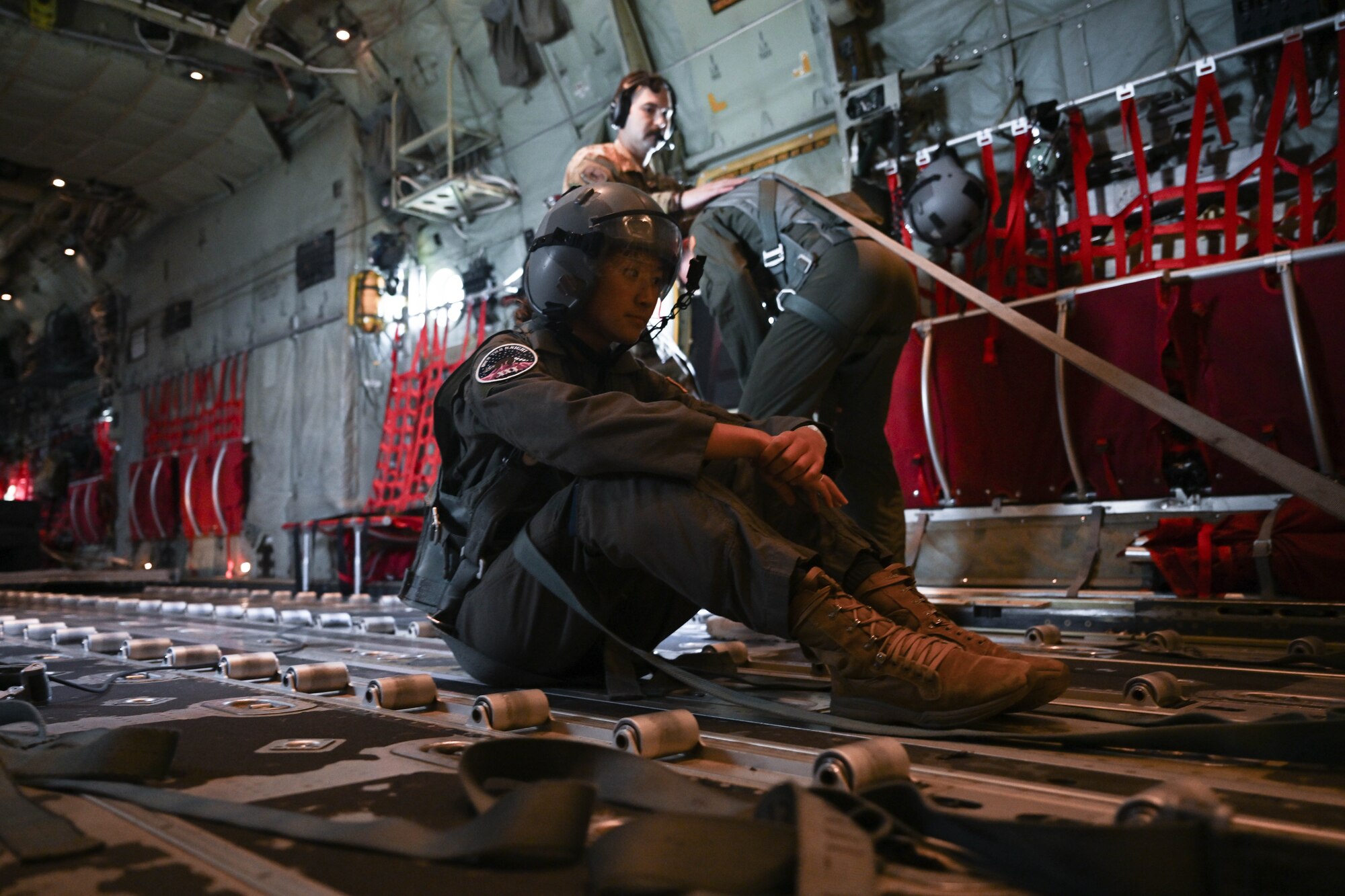 A woman in uniform sits inside a military aircraft.