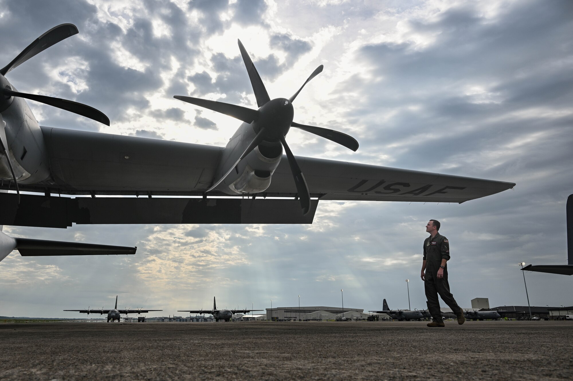 A man in uniform walks around a military aircraft.
