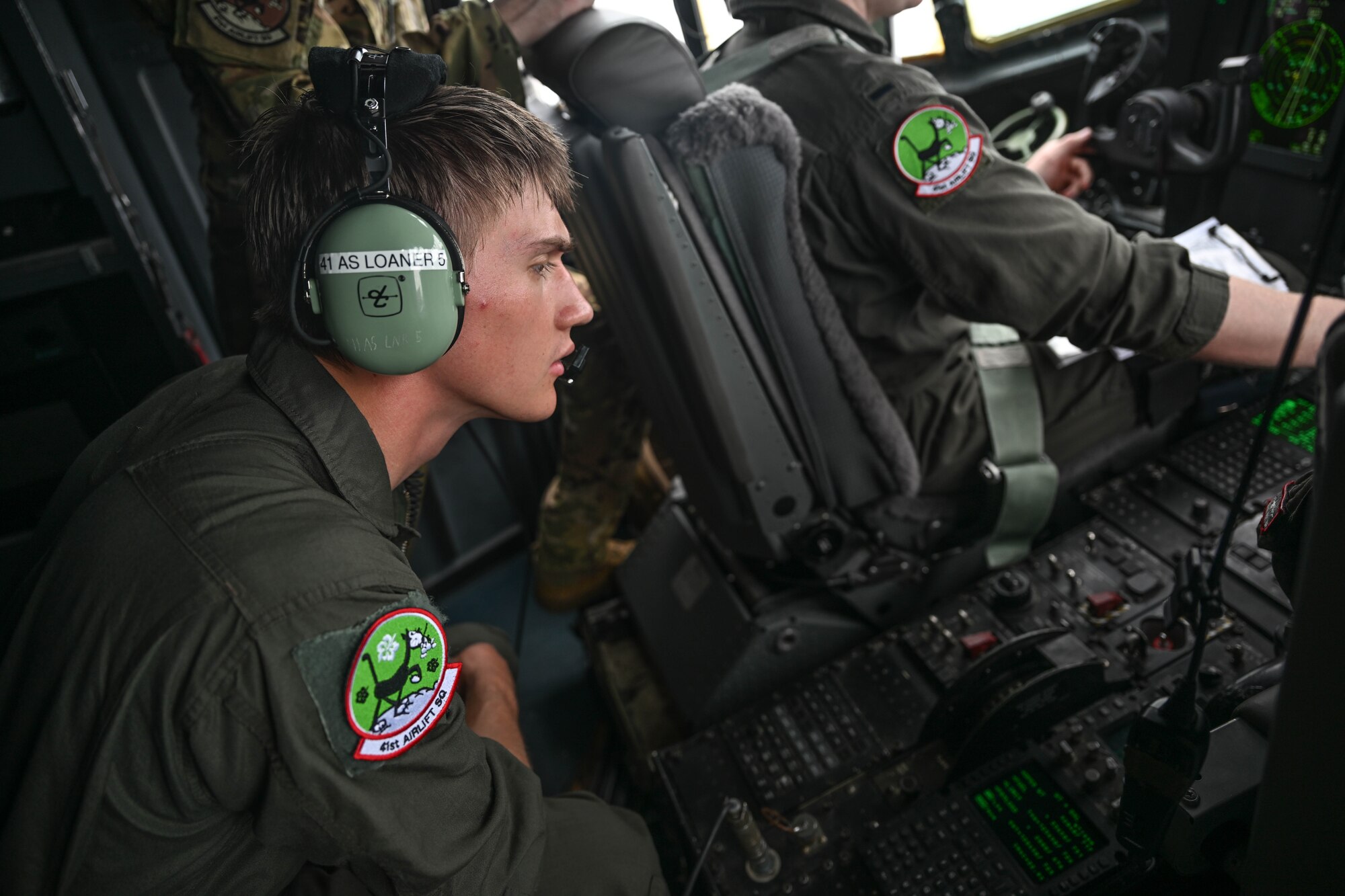 A man in uniform looks at the controls in the flight deck of a c-130.