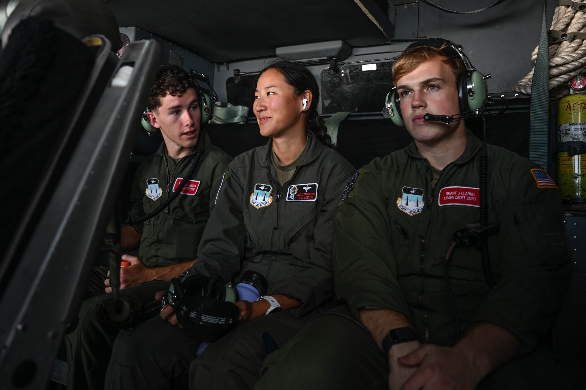 Three people in uniform sit next to each other in a plane.