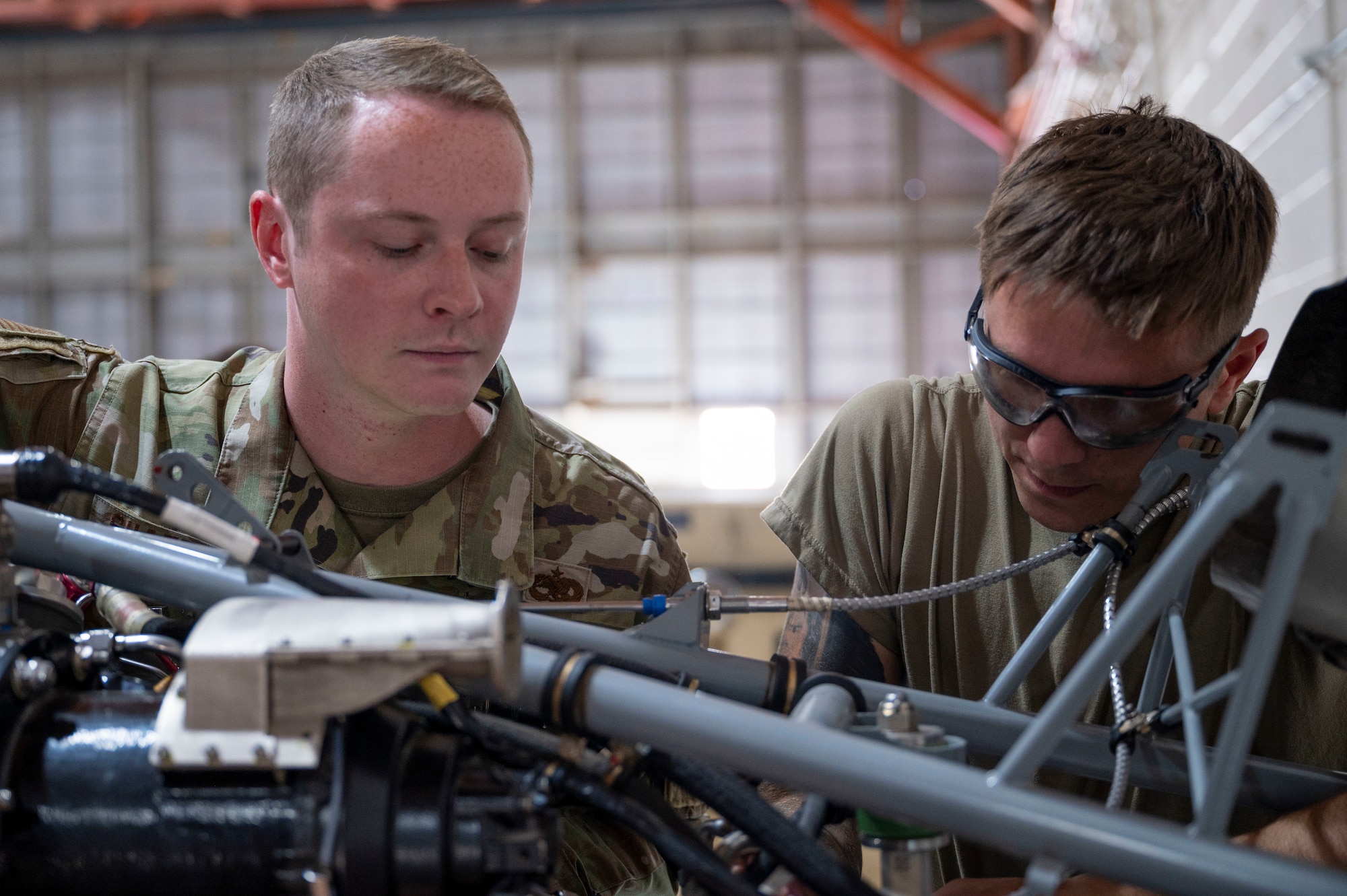 U.S. Air Force Staff Sgt. Shaun Shaffer, 49th Aircraft Maintenance Squadron dedicated crew chief, left, oversees as U.S. Air Force Austin James, 49th AMXS MQ-9 Reaper aircraft apprentice, does a fuel nozzle installation at Holloman Air Force Base, New Mexico, July 10, 2024.
