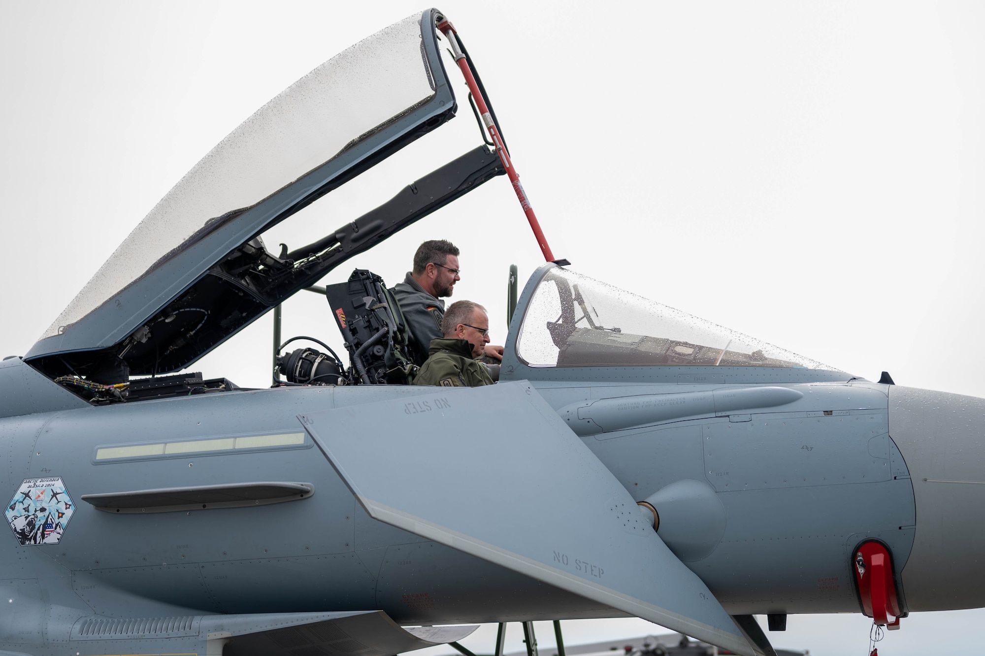 2 maintainers assigned to the German Air Force sit in the cockpit of a Rafale aircraft to conduct maintenance.