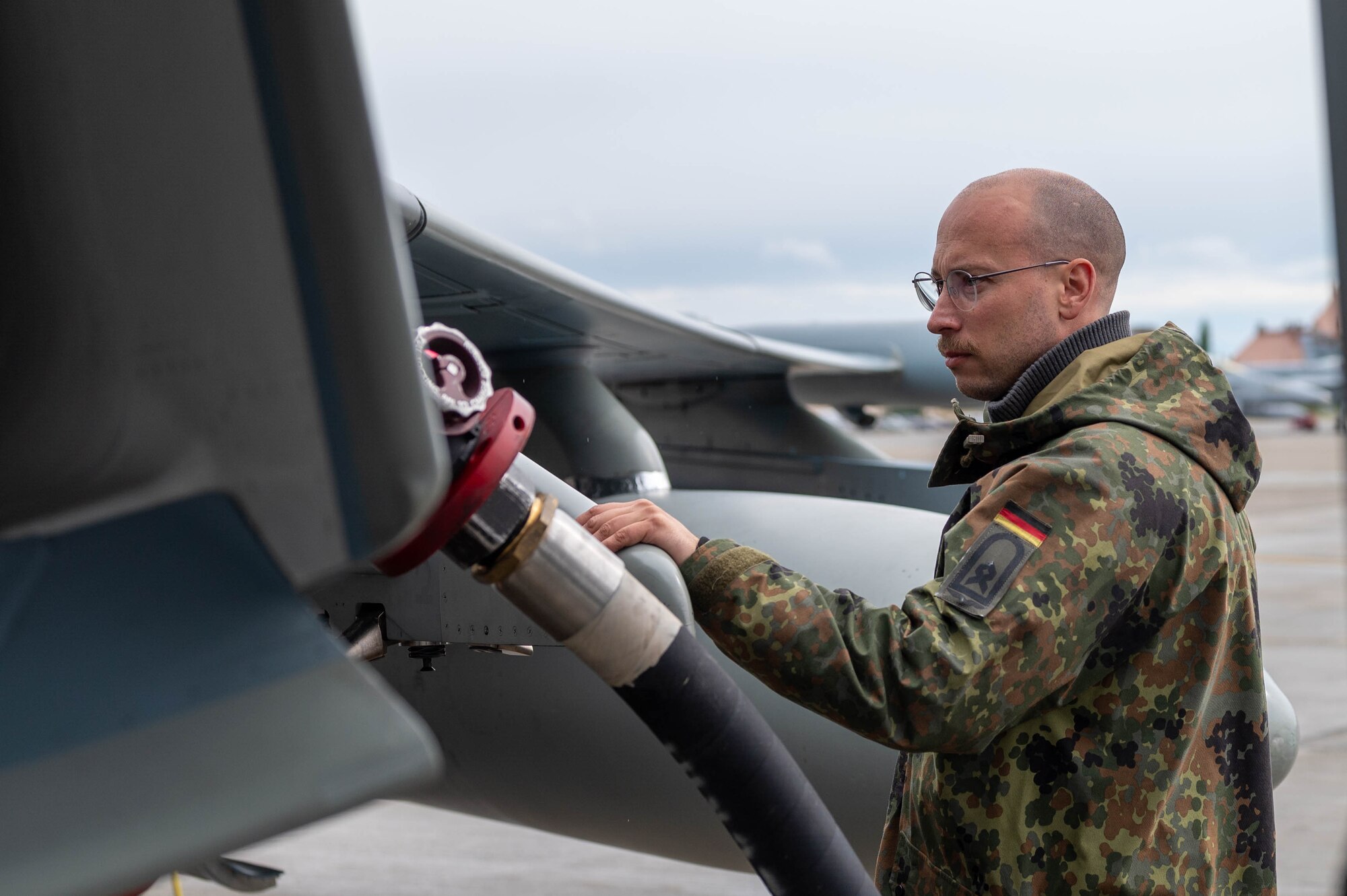 A maintainer from the German Air Force refuels a Rafale jet.