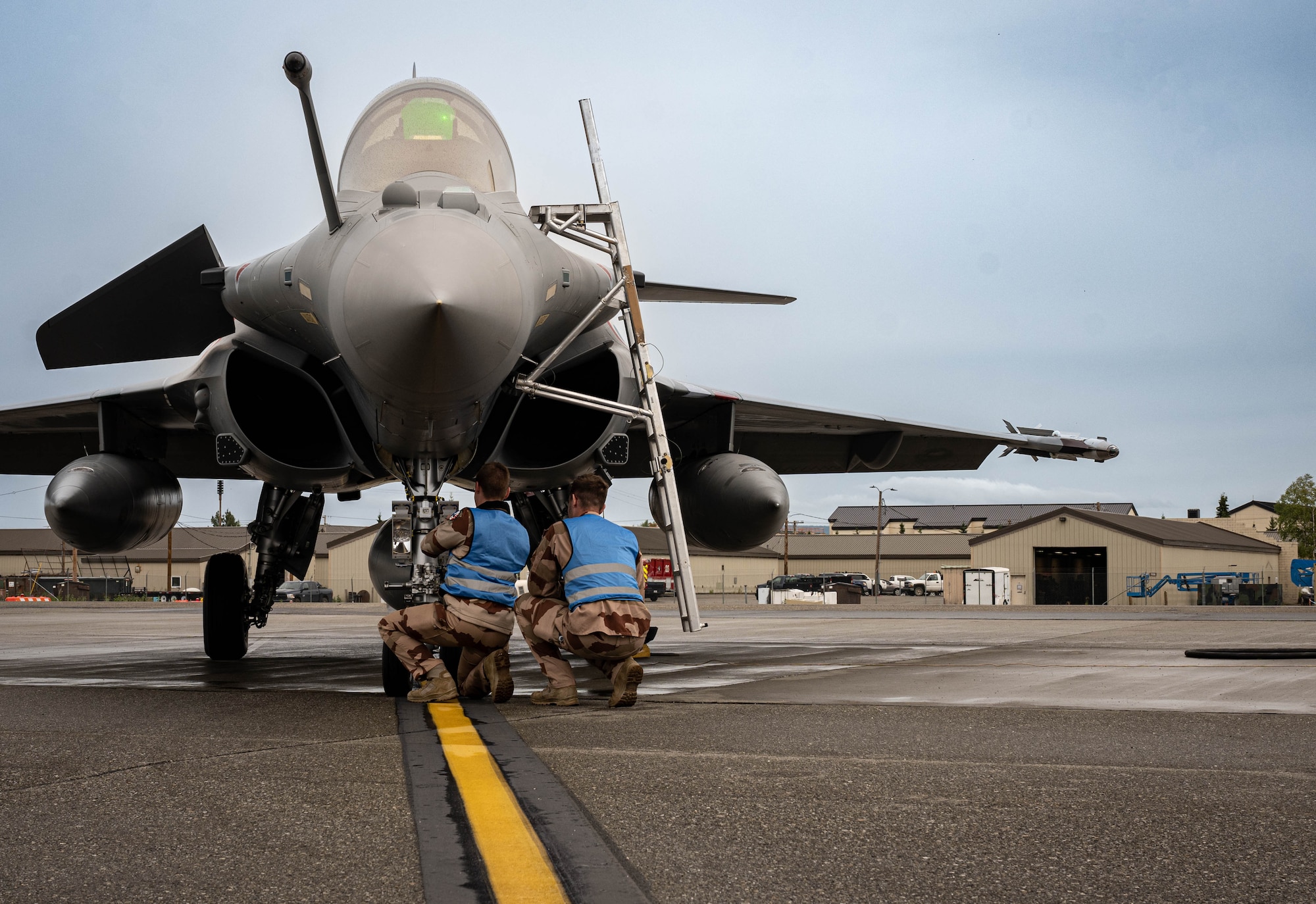 French Air and Space Force avionic technicians perform routine maintenance on the wheel of a Rafale fighter jet  on the flightline.