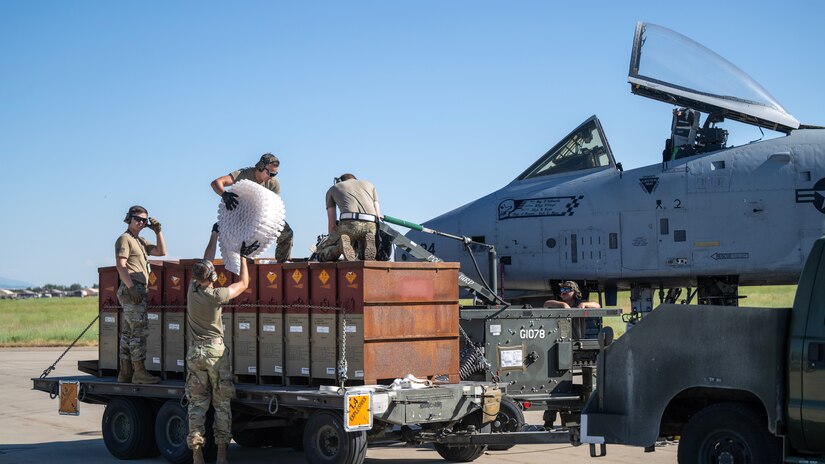 Airmen work next to an aircraft on a tarmac.