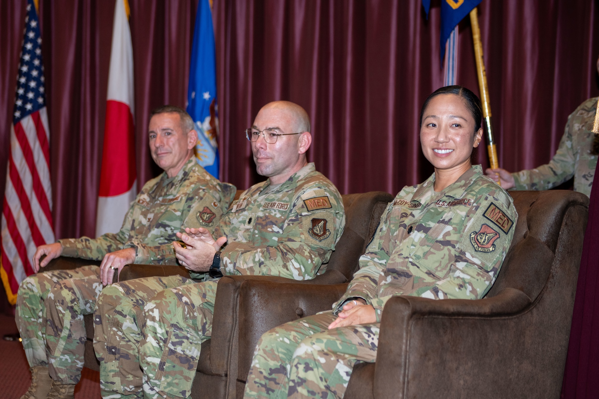 Col. Michael McCarthy, 374th Medical Group deputy group commander; Lt. Col. Darrick Duran, 374th Operational Medical Readiness Squadron outgoing commander, and Lt. Col. Kimberly McCoy-Singh, 374th OMRS incoming commander, sit on stage during a change of command ceremony.