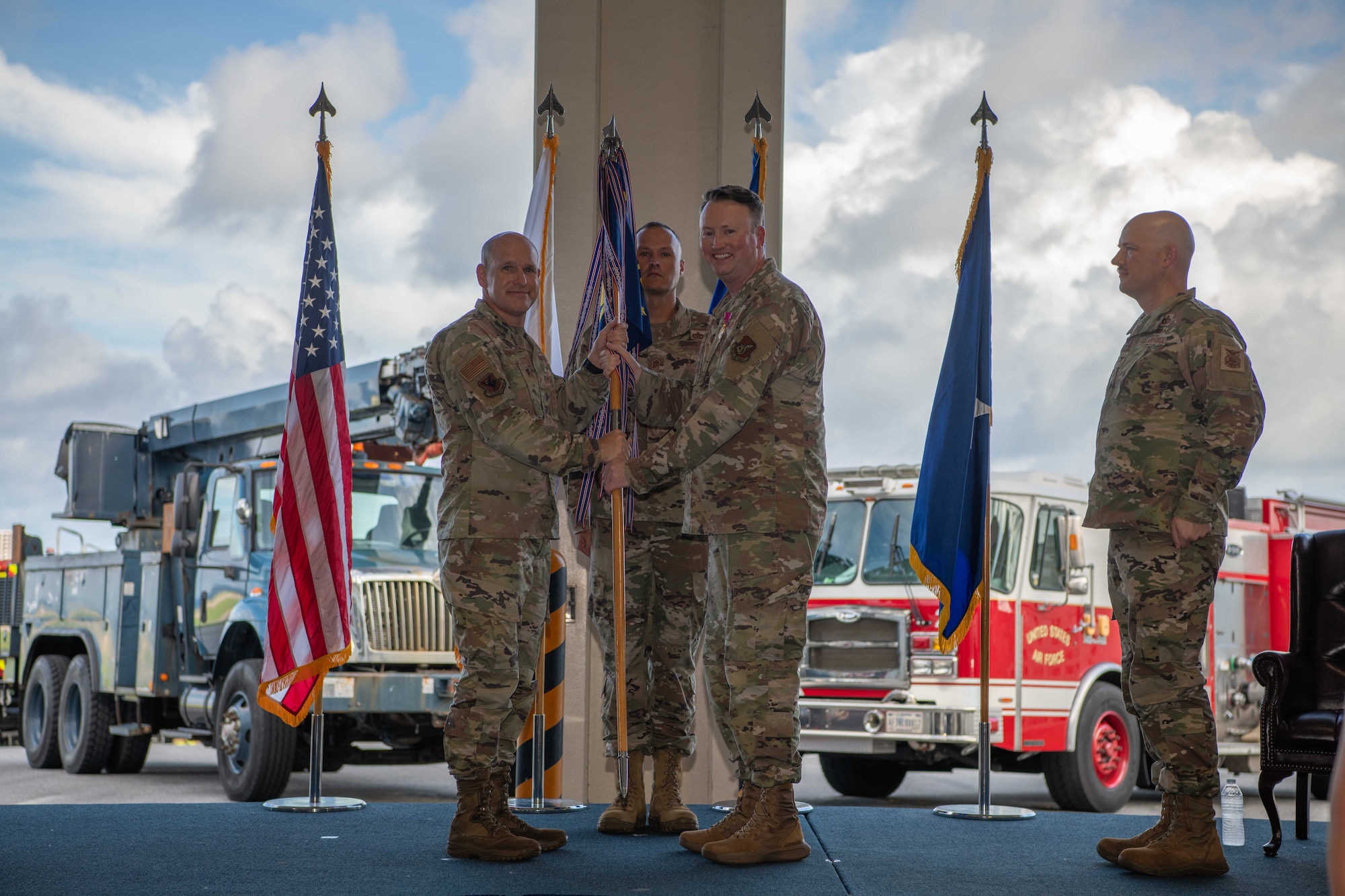 military members stand on a stage with a guide on stick