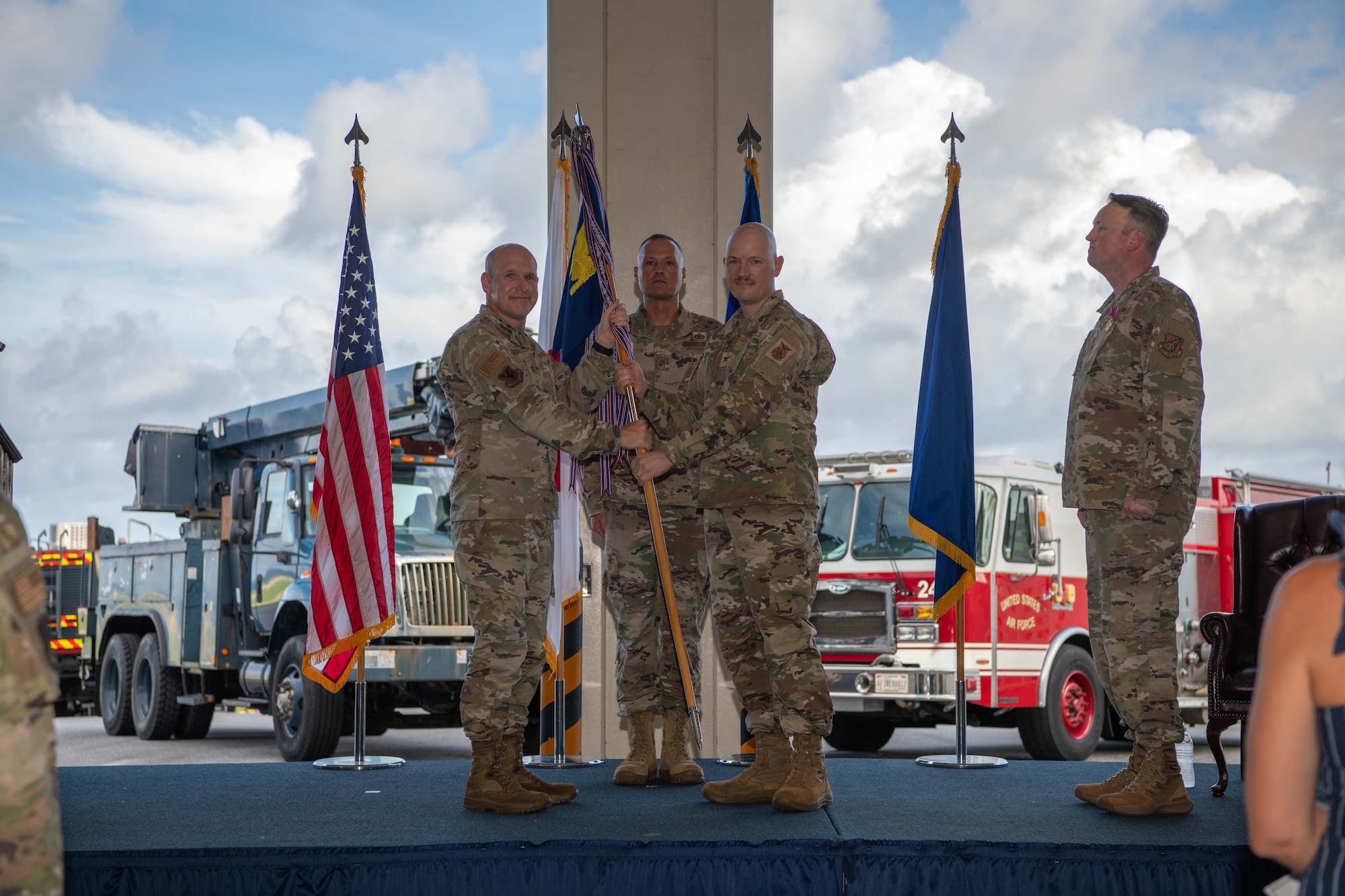 military members stand on a stage with a guide on stick