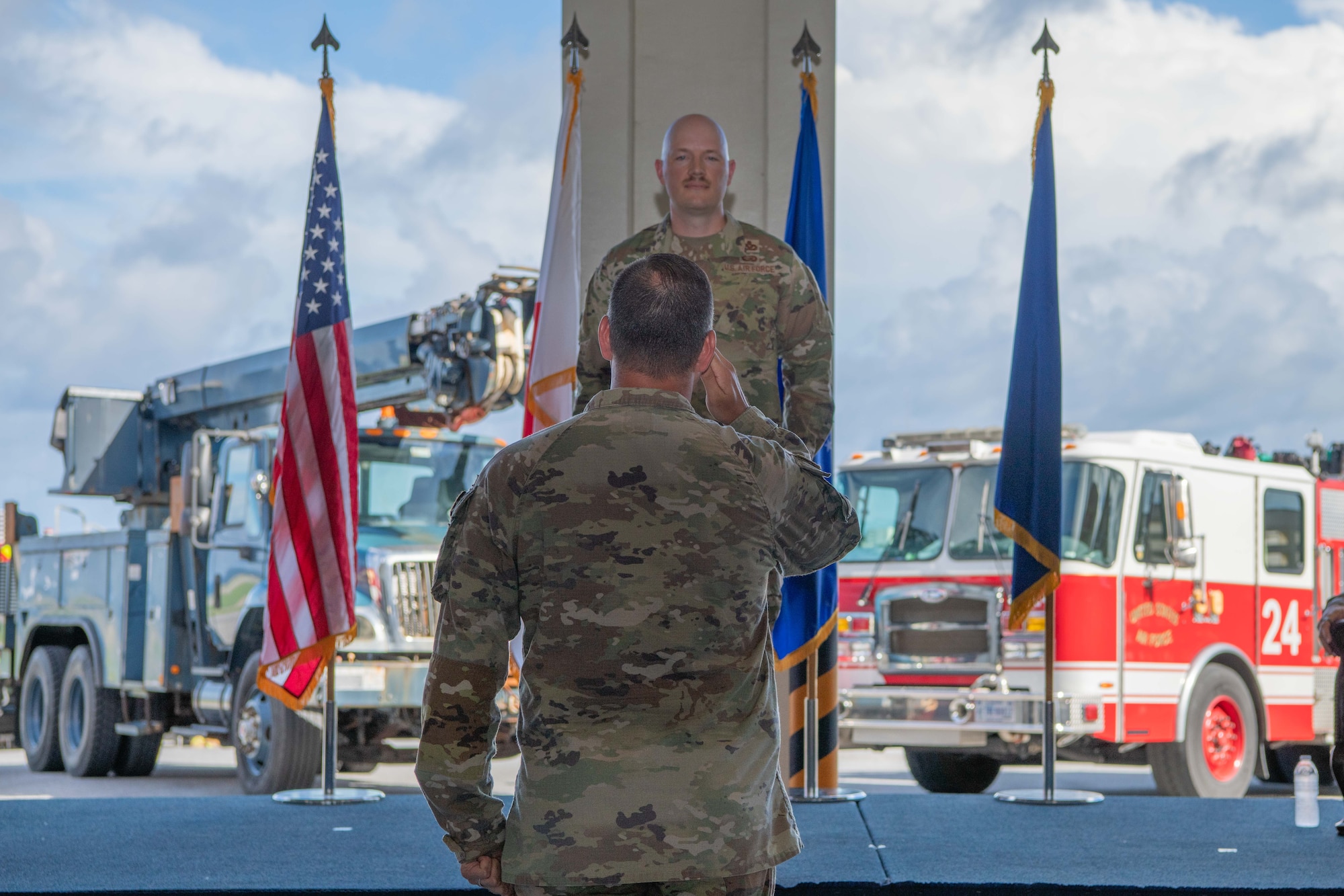 military member salutes another military member on a stage