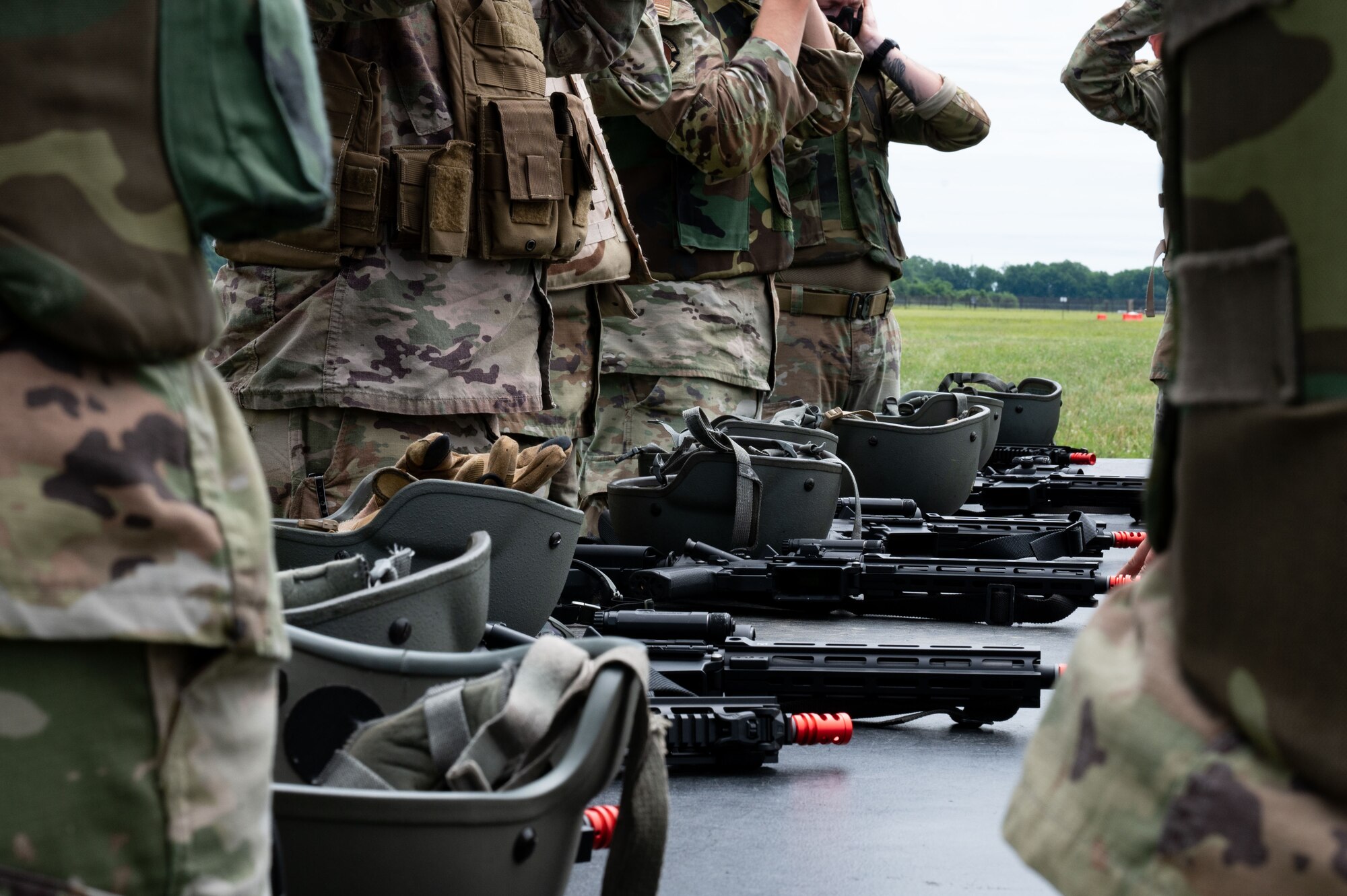 A line of airsoft rifles rests on a table before an exercise at the Tactics and Leadership Nexus training site at Dover Air Force Base, Delaware, July 11, 2024. The airsoft rifles shoot small, plastic spheres that are safer and don’t break the skin’s barrier, unlike the M4 shot with simunition non-lethal training rounds. (U.S. Air Force photo by Airman Liberty Matthews)