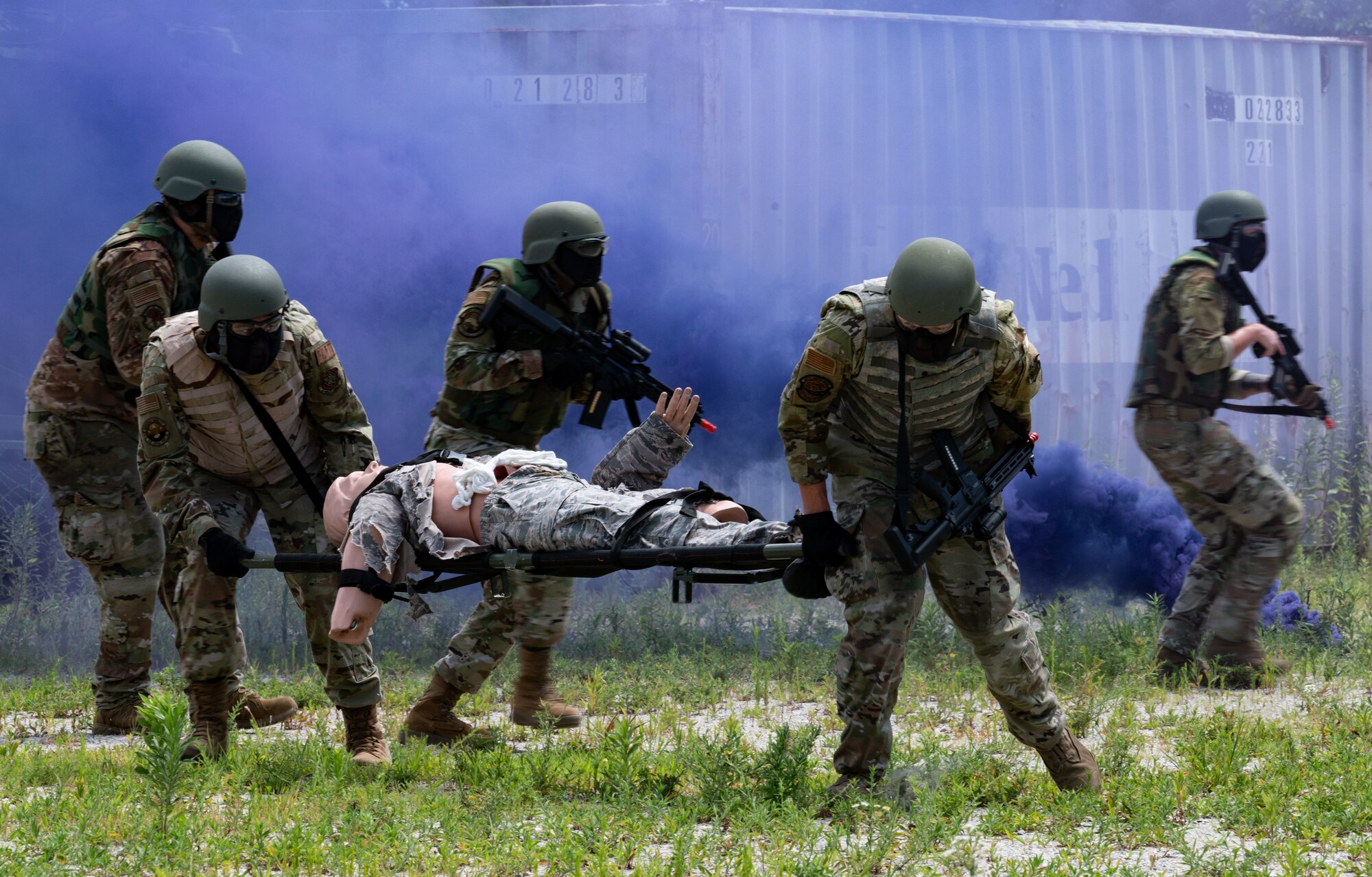 A group of U.S. Airmen defend a mannequin on a stretcher during a training exercise at the Tactics and Leadership Nexus training site at Dover Air Force Base, Delaware, July 11, 2024. The new airsoft rifles used during the exercises improved the deployment training experience, simulating a more realistic approach to carrying and firing weapons while also being a safer and easier option over an M4 rifle using simunition non-lethal training rounds.  (U.S. Air Force photo by Airman Liberty Matthews)