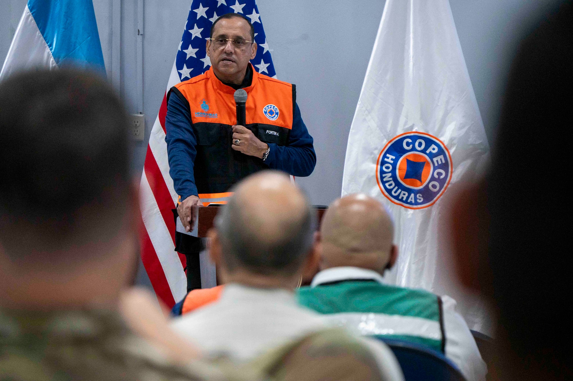 A photo of a person speaking at a podium with a microphone.