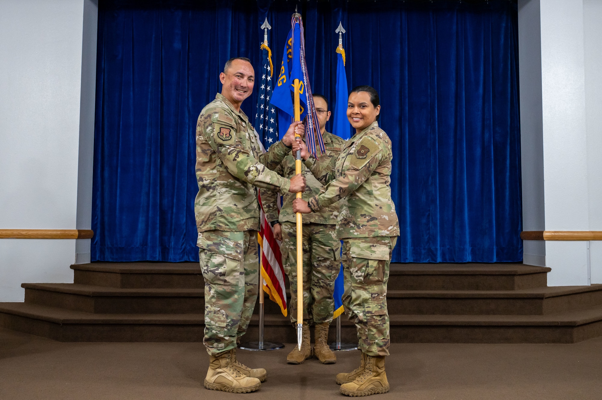 Col. John Dines passes the guidon during an assumption of command ceremony to Maj. Rebecca Nolasco.