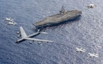 Air Force B-52 Stratofortress leads five other aircraft in formation above aircraft carrier USS Theodore Roosevelt during routine operations in
Philippine Sea, February 24, 2024