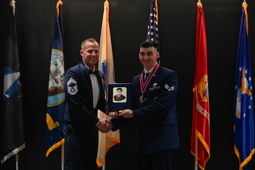 U.S. Air Force Chief Master Sgt. Michael Nolan, 17th Communication Squadron senior enlisted leader, gives Senior Airman Lane Young, 315th Training Squadron, the John L. Levitow Award at the Airman Leadership School class 24-E at the Powell Event Center, Goodfellow Air Force Base, Texas, July 11, 2024. The John Levitow Award is the highest honor presented to an ALS graduate. (U.S. Air Force photo by Airman 1st Class Brian Lummus)