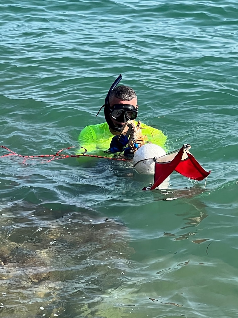 A fisherman resurfaces with a spiny mini lobster during the 2022 Lobster Mini Season off Bill Bags Cape Florida State Park in Key Biscayne, Florida, July 27, 2022. Lobster Mini Season is an annual event during which the U.S. Coast Guard and Florida Fish and Wildlife Conservation Commission ramp up safety inspections and fishery boardings to enforce state and federal fishery laws. (U.S. Coast Guard photo by Scott Szczepaniak)