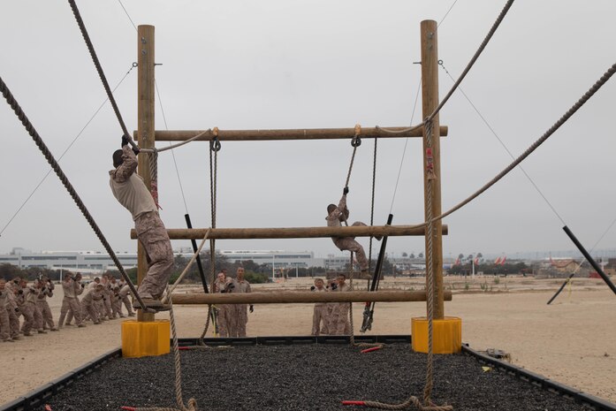 A U.S. Marine Corps recruit with Kilo Company, 3rd Recruit Training Battalion, executes an obstacle during a confidence course event at Marine Corps Recruit Depot San Diego, California, July 1, 2024. The confidence course challenged recruits physically and mentally through obstacles that require confidence in their strength, balance, and determination. (U.S. Marine Corps photo illustration by Cpl. Elliott A. Flood-Johnson)