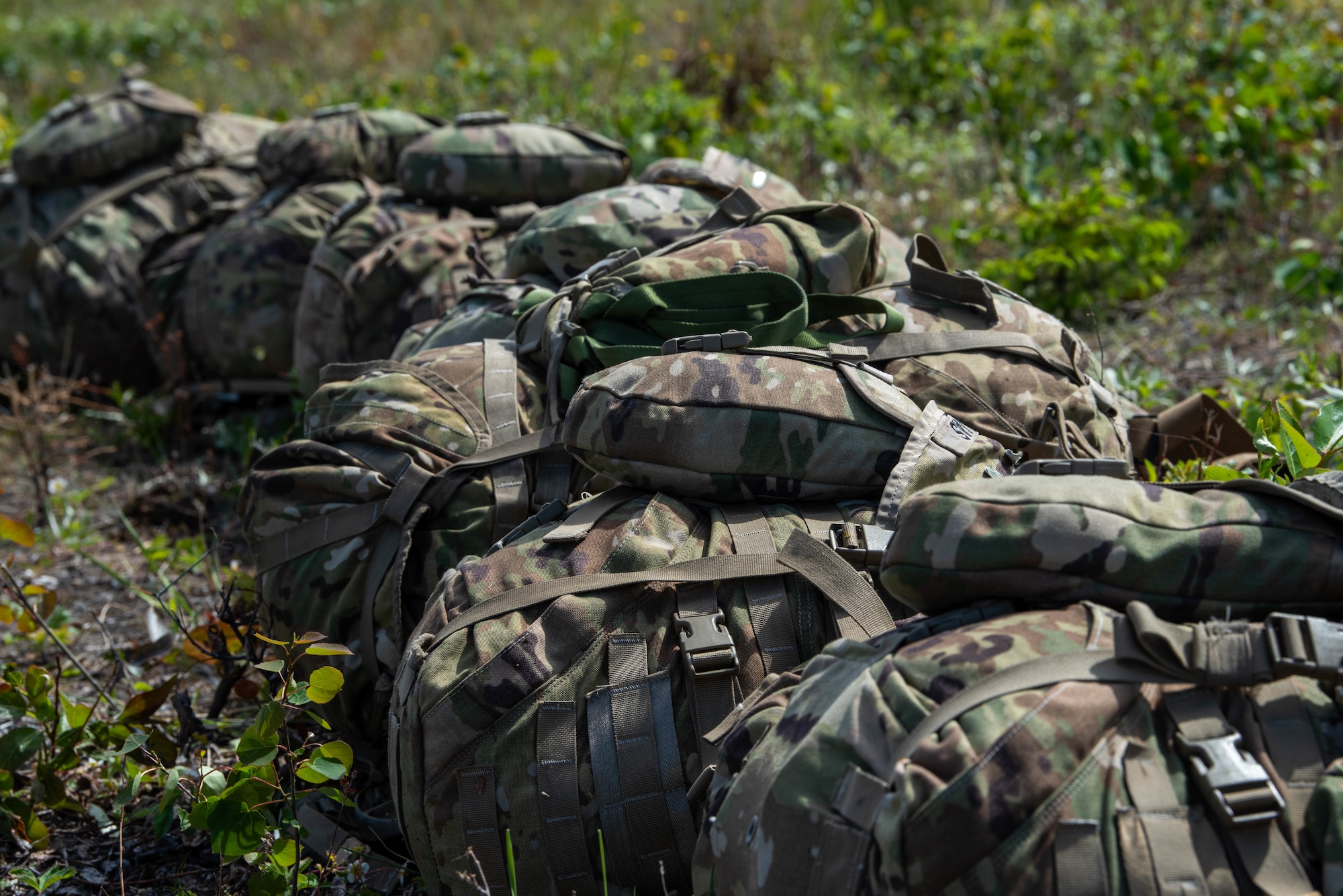 Operational camouflage pattern backpacks from the U.S. Army 11th Division Airborne lay on the ground.