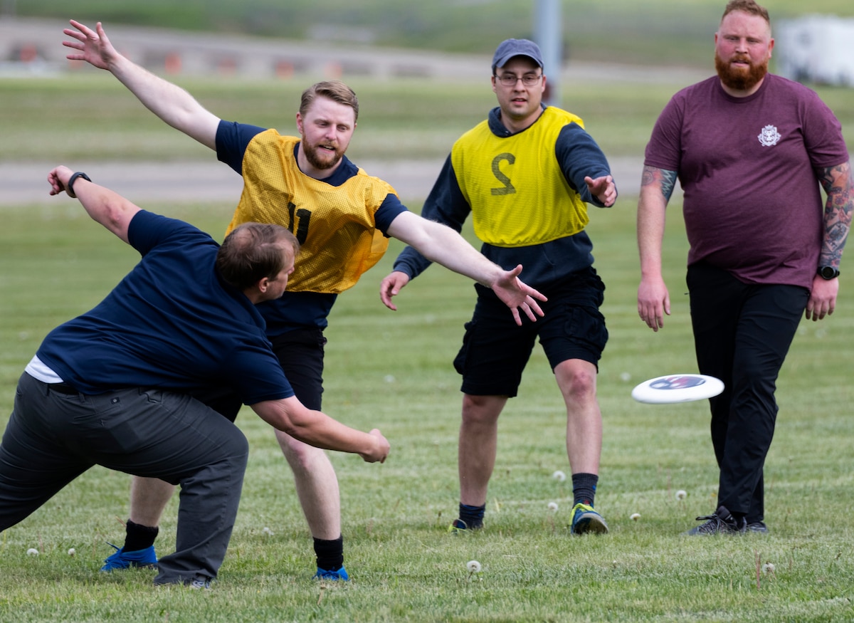A man throws a flying disk past people with their arms extended to block it.