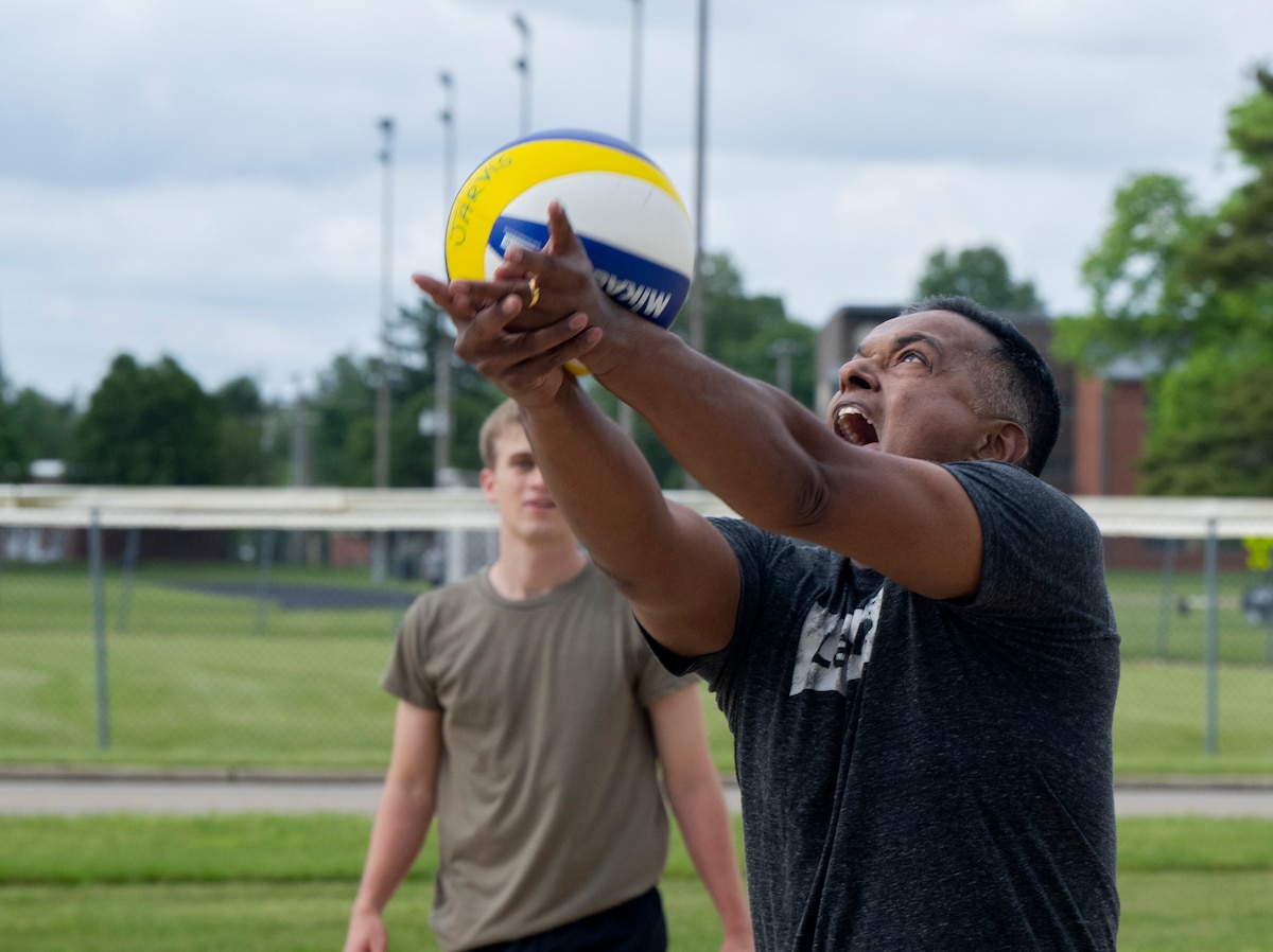 A man makes a face as he hits the volleyball with his forearms.