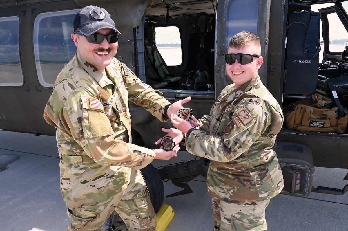 Staff Sgt. Kaden Ables, 433rd Contingency Response Flight specialist, swapped military patches with Army Chief Warrant Officer 2 Matthew Minjarez, 5th Battalion, 101st Aviation Combat Brigade UH-60 Black Hawk pilot after Ables marshalled the pilot onto the flightline at the Contingency Location Operations Rehearsal (CLOR 24) in Alpena, Michigan June 24, 2024.