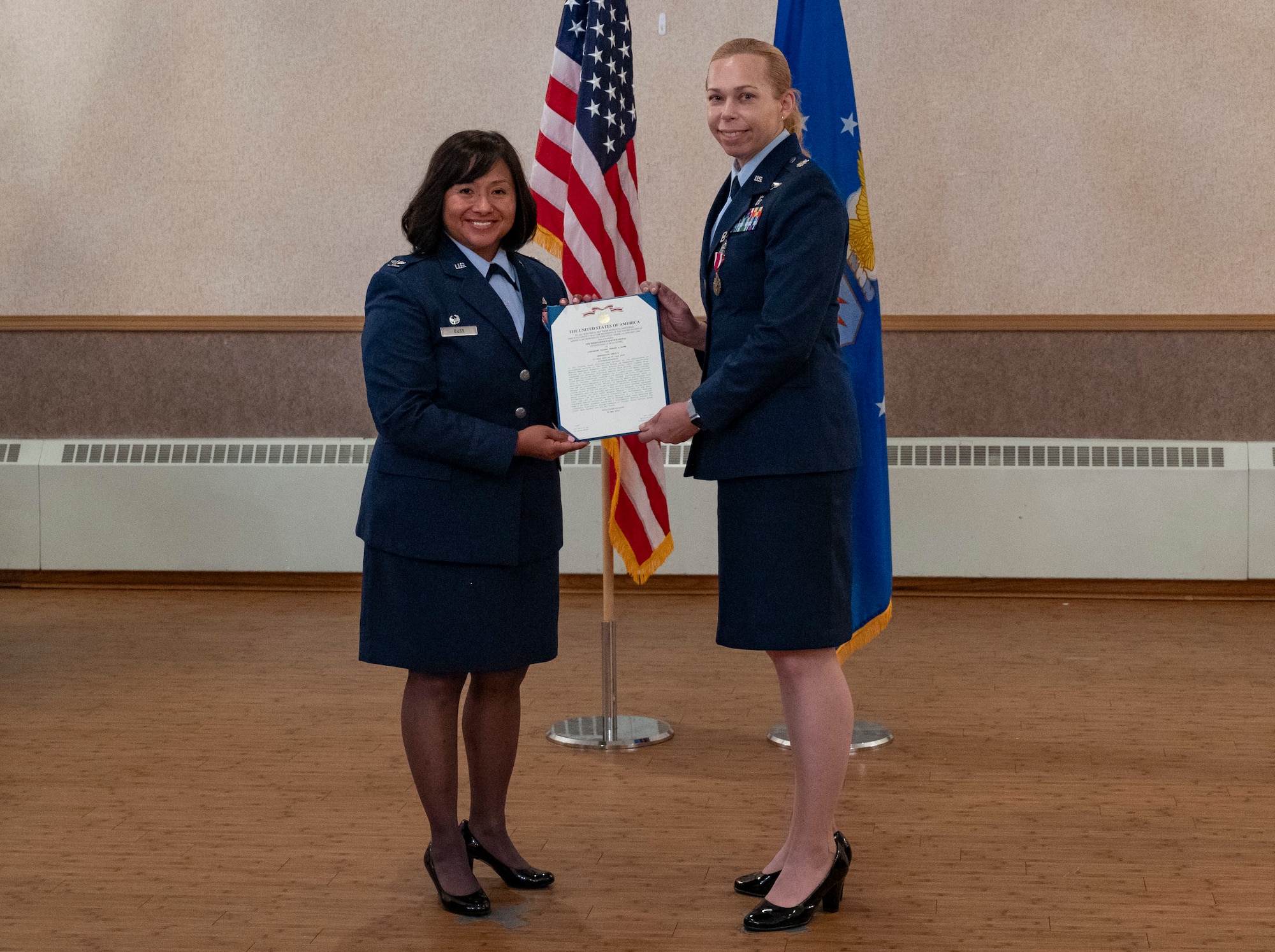 U.S. Air Force Col. Farrah Buss, 354th Medical Group commander, hands a meritorious service medal certificate to Lt. Col. Chelsea Payne.